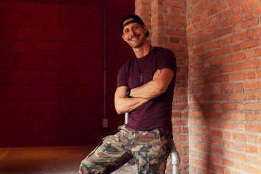 Neşeli bir gülümseme çekici yüzüne sahip yakışıklı genç Kafkas hipster siyah şapkalı kız sokakta için beklerken çapraz el ile kameraya bakarak aksesuarları keyfi yerinde olmak.