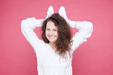 Neşeli mavi gözlü kıvırcık saçlı kadın yatay portre yakın kulakları gibi kafa üzerinde beyaz eldivenler eller tutar, dost sevimli tavşan taklit, geniş, Paskalya kutlamak için hazır gülümsüyor.