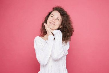 Dreamful pretty genç şık kadın, hafifçe gülümsüyor, yeni giysiler hakkında rüyalar ya da en iyi arkadaşı ile alışverişe gidiyor, kopya alanı ile pembe arka plan üzerinde izole belirli çekici bir görünüme sahiptir.