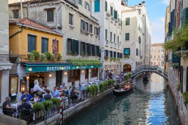 Venice, İtalya - 13 Ağustos 2017: Restoran insanlar Venedik'te gondol İtalya ile kanal ile kaldırım tablolarla 