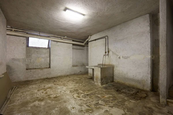 Basement with sink and dirty floor in old house interior