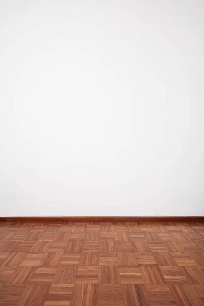 Empty room with dark wooden tiled floor and white blank wall