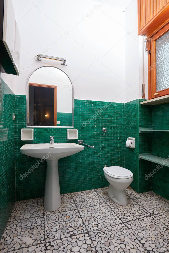 Old bathroom with green tiles in apartment interior