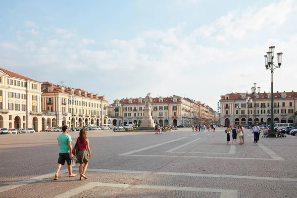 Piazza Galimberti con uomo e donna che passeggiano in una soleggiata giornata estiva, cielo azzurro a Cuneo . — Foto Stock