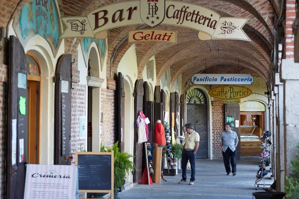 Arcade en ladrillos rojos alrededor Santuario de la iglesia de Vicoforte con gente y tiendas en un día de verano en Piamonte, Italia — Foto de Stock