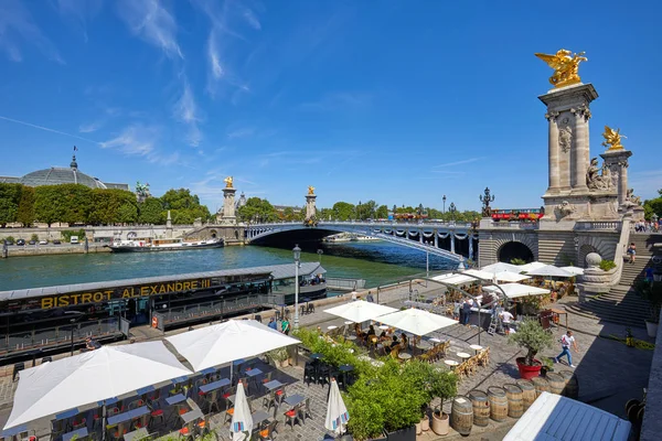 Ponte Alexandre III con persone e turisti e caffetteria nella zona dei moli in una giornata estiva soleggiata, cielo blu a Parigi, Francia . — Foto Stock