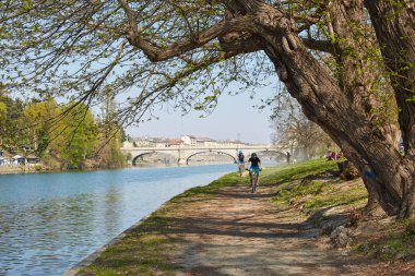 Güneşli bir günde ağaçlar, insanlar ve bisikletçiler ile Po nehir banka yolu, Piedmont mavi gökyüzü, Torino, İtalya.
