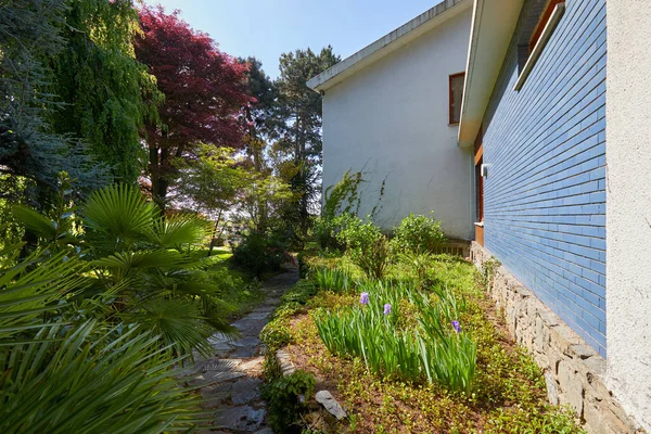 Giardino e villa con sentiero lastricato in pietra e piante in una giornata estiva soleggiata, Italia — Foto Stock