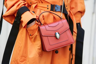 Fendi moda defilesinden önce kırmızı Bulgari çantalı ve turuncu trençkotlu kadın, Milano Moda Haftası 21 Eylül 2017 'de Milano' da.
