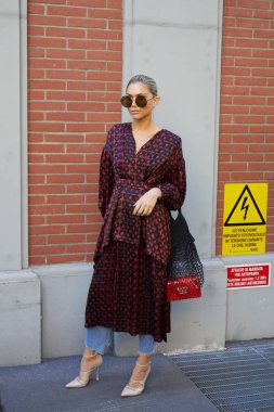 Fendi defilesinden önce kırmızı ve siyah elbiseli ve güneş gözlüklü kadın, Milano Moda Haftası 21 Eylül 2017 'de Milano' da.