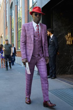 Fendi defilesi öncesi mor damalı takım elbiseli ve kırmızı şapkalı adam, Milano Moda Haftası sokak stili 21 Eylül 2017'de Milano'da.
