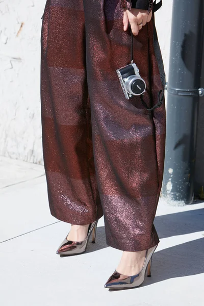 Kvinna med glitter brons byxor, metalliska skor och Nikon kamera före Alberto Zambelli modevisning, Milan Fashion Week street style den 20 september 2017 i Milano. — Stockfoto