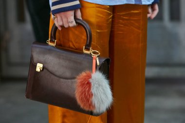 Giorgio Armani moda defilesinden önce altın ipek pantolonlu ve kahverengi deri çantalı kadın, Milan Moda Haftası tarzı 22 Eylül 2017 'de Milano' da.