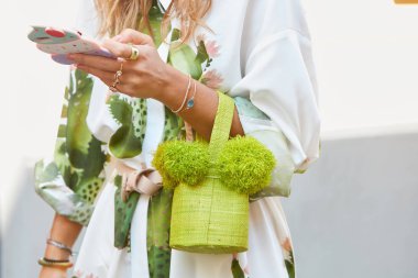 22 Eylül 2017 'de Milano' da, Sportmax moda defilesinden önce yeşil çantalı, mücevherli ve dondurmalı akıllı telefon kılıflı bir kadın..