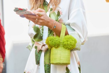 22 Eylül 2017 'de Milano' da, Sportmax moda defilesinden önce yeşil çantalı, mücevherli ve dondurmalı akıllı telefon kılıflı bir kadın..