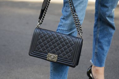 Woman with black leather Chanel bag before Giorgio Armani fashion show, Milan Fashion Week street style on September 22, 2017 in Milan.