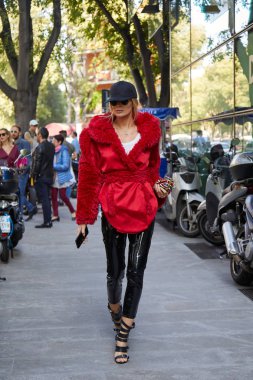 Woman with red jacket with fur and black cap walking before Giorgio Armani fashion show, Milan Fashion Week street style on September 22, 2017 in Milan. clipart