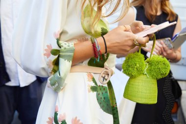 Beyaz ve pastel renkli elbiseli ve yeşil çantalı bir kadın Sportmax moda defilesinden önce akıllı telefona bakıyor, Milan Moda Haftası tarzı 22 Eylül 2017, Milano.