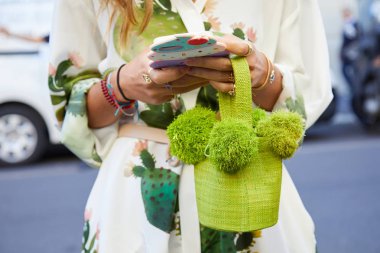 Spor defilesinden önce beyaz ve pastel renkli elbiseli ve yeşil çantalı kadın, Milan Moda Haftası tarzı 22 Eylül 2017 'de Milano' da.