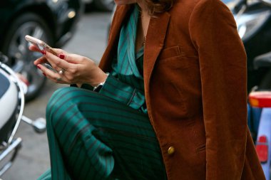 Yeşil ipek pantolonlu, kahverengi ceketli, Antonio Marras moda defilesinden önce akıllı telefona bakan kadın, Milan Moda Haftası tarzı 23 Eylül 2017, Milano.