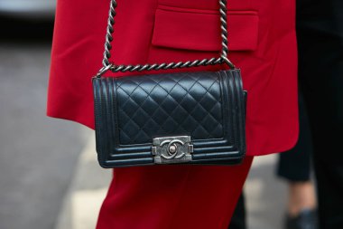 23 Eylül 2017 'de Milan' da, Antonio Marras moda defilesinden önce siyah deri çantalı ve kırmızı takım elbiseli bir kadın..