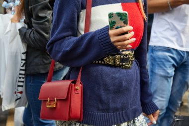 23 Eylül 2017 'de Milan Moda Haftası' nda Antonio Marras defilesinden önce kırmızı Saint Laurent deri çantalı ve palmiye yapraklı akıllı telefon kılıflı bir kadın..