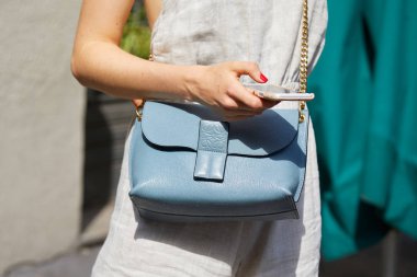 Loewe marka, altın zincirli, soluk mavi deri çantalı kadın Blumarine moda defilesinden önce akıllı telefona bakıyor, Milan Moda Haftası tarzı 23 Eylül 2017, Milano.