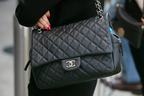 Woman with black leather Chanel bag before Giorgio Armani fashion show, Milan Fashion Week street style on September 22, 2017 in Milan.