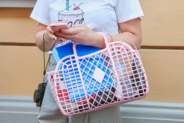 Frau mit rosa Plastiktüte schaut auf Smartphone mit weißem T-Shirt mit Eis vor sportmax Modenschau, Mailänder Modewoche Streetstyle am 22. September 2017 in Mailand. — Stockfoto