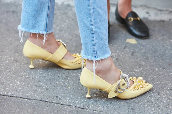 Mujer con zapatos decorados de tacón alto amarillo y pantalones vaqueros azules desgarrados antes del desfile de moda Sportmax, Milan Fashion Week street style on septiembre 22, 2017 in Milan . — Foto de Stock