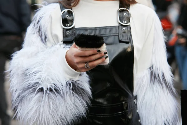 Kvinna med vita pälsfodral och svart läder totalt tittar på smartphone med pälsöverdrag innan Versace modevisning, Milan Fashion Week street style den 22 september 2017 i Milano. — Stockfoto