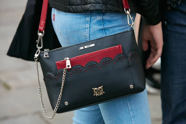 Mulher com eu amo Moschino saco de couro preto com carteira vermelha e jeans Levi azul antes Versace desfile de moda, Milan Fashion Week street style em setembro 22, 2017 em Milão . — Fotografia de Stock