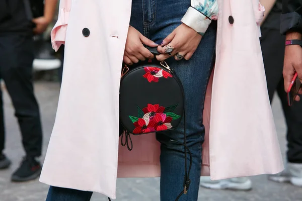 Vrouw met roze jas en zwarte leren tas met rode bloemen borduurwerk voor Versace modeshow, Milaan Fashion Week straatstijl op 22 september 2017 in Milaan. — Stockfoto