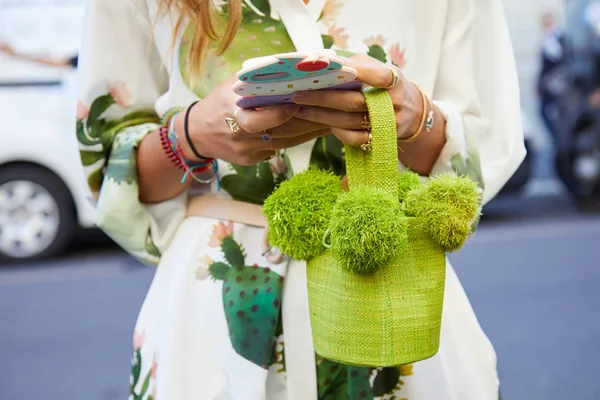 Spor defilesinden önce beyaz ve pastel renkli elbiseli ve yeşil çantalı kadın, Milan Moda Haftası tarzı 22 Eylül 2017 'de Milano' da.
