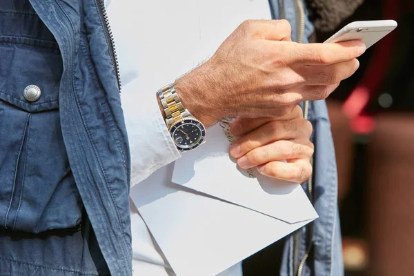 Мужчина с Rolex Submariner в стали и золоте смотрит на смартфон перед показом моды в стиле стрит-арта на Неделе моды в Милане 23 сентября 2017 года . — стоковое фото