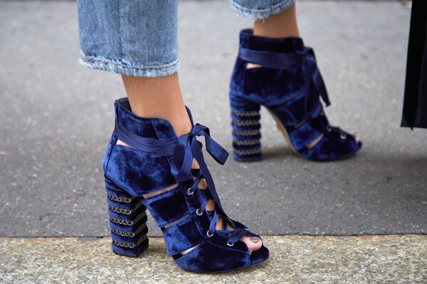 Женщина в синей бархатной обуви на высоком каблуке с атласной лентой перед показом мод Ermanno Scervino, уличный стиль Недели моды в Милане 23 сентября 2017 года в Милане
.