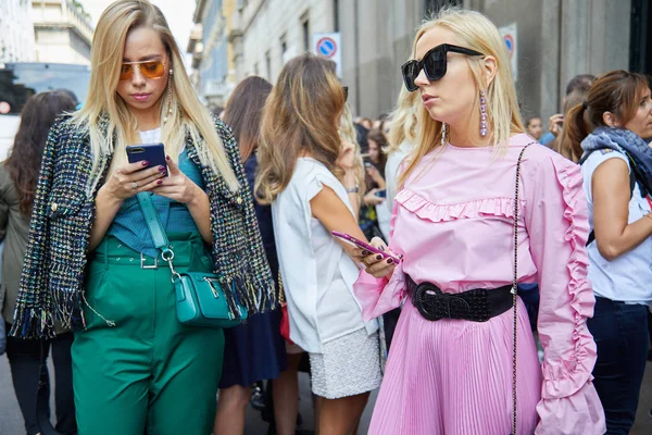 Mujeres con ropa verde y rosa mirando el teléfono inteligente antes de Ermanno Scervino desfile de moda, Milán Fashion Week street style en septiembre 23, 2017 en Milán . — Foto de Stock