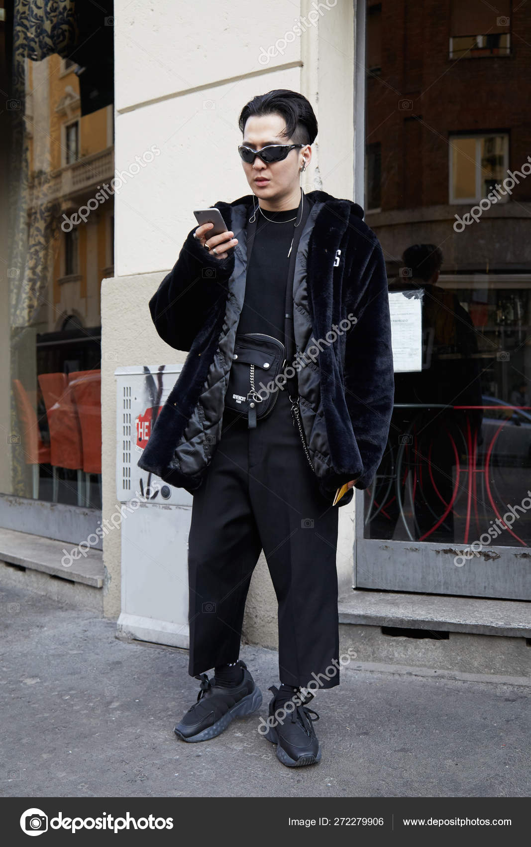 Hombre con abrigo de piel GCDS negro mirando el teléfono inteligente antes del desfile de moda Daks, Fashion Week street style on enero 14, 2018 in Milan . — editorial