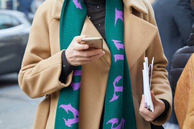 Bej paltolu, kırmızı ve mor fularlı adam moda öncesi telefona bakıyor Albino Teodoro gösterisi, Milano Moda Haftası sokak stili 21 Şubat 2018'de Milano'da.