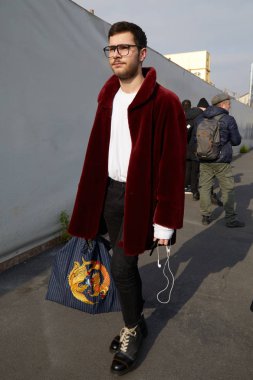 Dsquared 2 defilesinden önce koyu kırmızı kürk mantolu ve altın ejderli çantalı adam, Milano Moda Haftası sokak stili 14 Ocak 2018'de Milano'da.