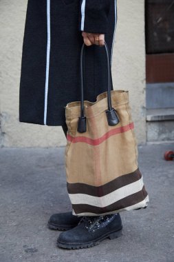 Daks defiles öncesi kahverengi, siyah beyaz renklerde çantalı adam, Milano Moda Haftası sokak stili 14 Ocak 2018'de Milano'da.