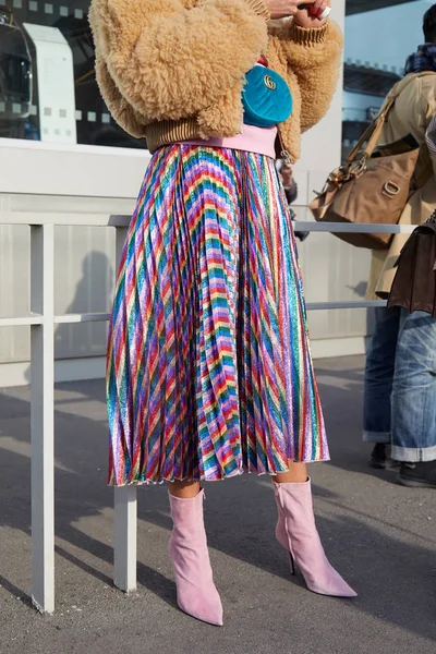 2018年2月21日にミラノで開催されるグッチファッションショーの前に、メタリックカラフルなストライプスカートとブルーベルベットポーチを持つ女性、ミラノファッションウィークストリートスタイル. — ストック写真