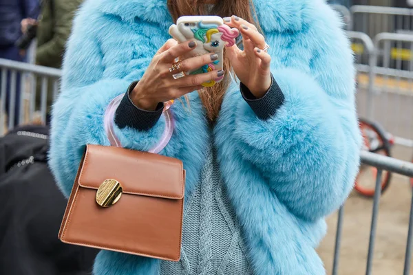 MILAN - FEBRUARY 22: Woman with blue fur coat looking at smartph — стокове фото