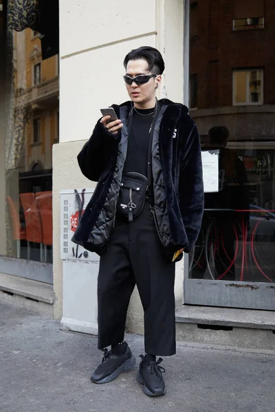 Człowiek z czarnym Gcds futro patrząc na smartfon przed DAKS pokaz mody, Milan Fashion Week Street Style 14 stycznia 2018 w Mediolanie. — Zdjęcie stockowe