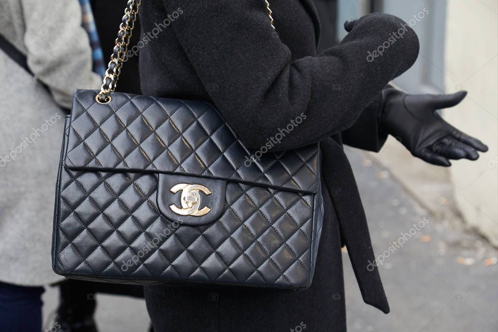 MILAN - FEBRUARY 21: Woman with large Chanel leather bag with golden logo before fashion Albino Teodoro show, Milan Fashion Week street style on February 21, 2018 in Milan.