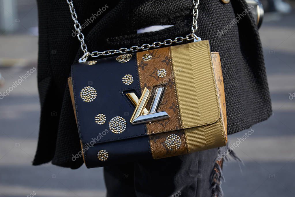 MILAN - FEBRUARY 21: Woman with beige, brown and blue Louis Vuitton bag with golden and silver logo before Gucci fashion show, Milan Fashion Week street style on February 21, 2018 in Milan.