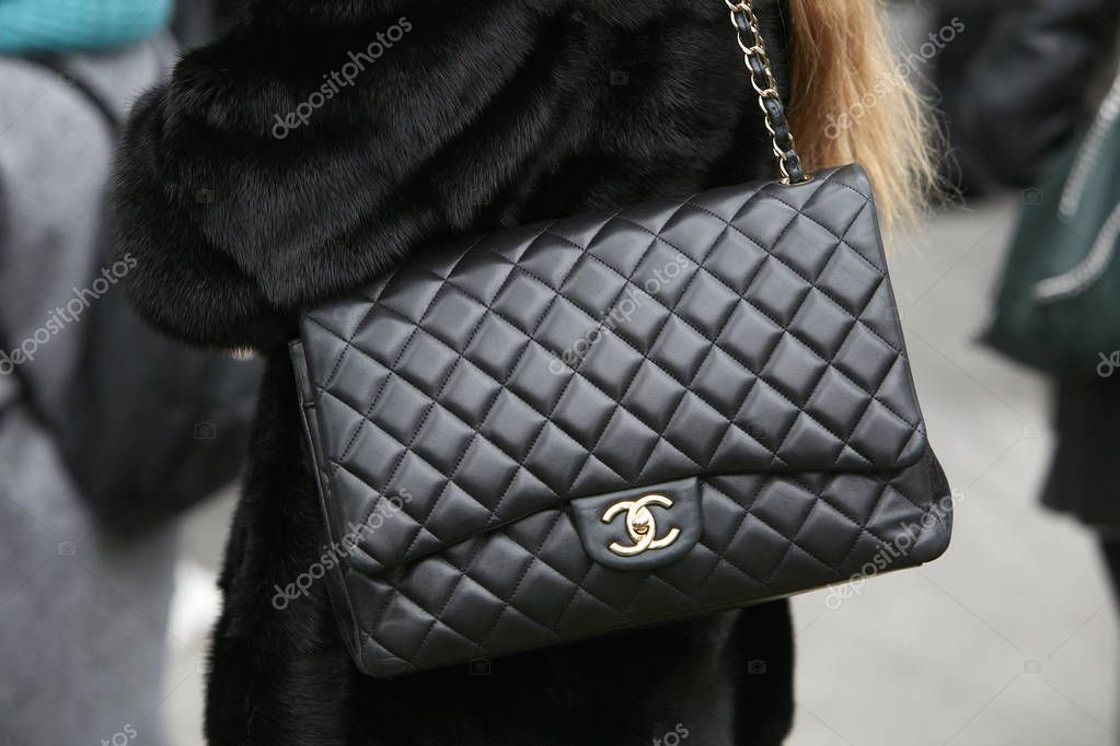 MILAN - FEBRUARY 25: Woman with black Chanel leather bag with golden chain and logo before Emporio Armani fashion show, Milan Fashion Week street style on February 25, 2018 in Milan.