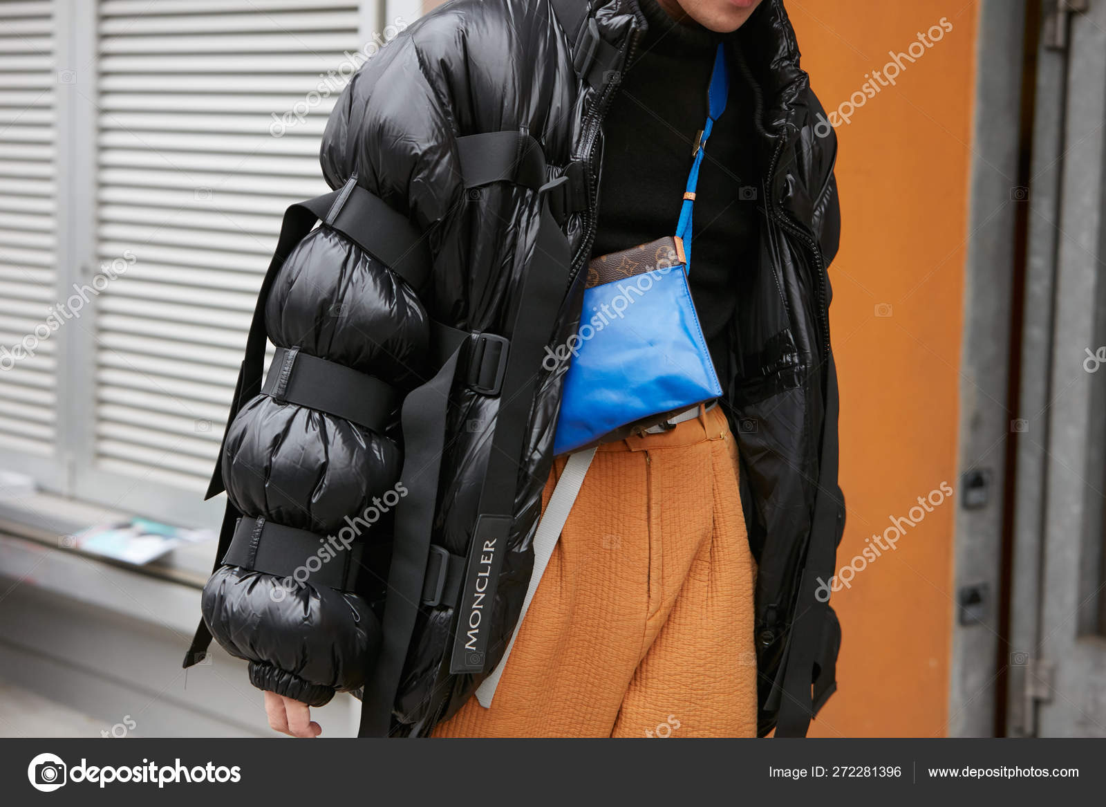 Man with black Moncler padded jacket, yellow trousers and blue Louis Vuitton  bag before Giorgio Armani fashion show, Milan Fashion Week street style on  January 15, 2018 in Milan. – Stock Editorial