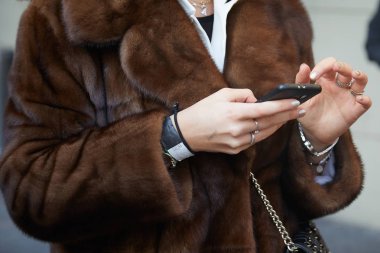 Daks moda defilesinden önce akıllı telefona bakan kahverengi kürklü kadın, Milan Moda Haftası tarzı 14 Ocak 2018, Milano.
