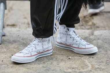 Fendi defilesinden önce beyaz Jw Anderson Converse ayakkabı ve siyah Adidas pantolonlu adam, Milano Moda Haftası sokak stili 15 Ocak 2018'de Milano'da.